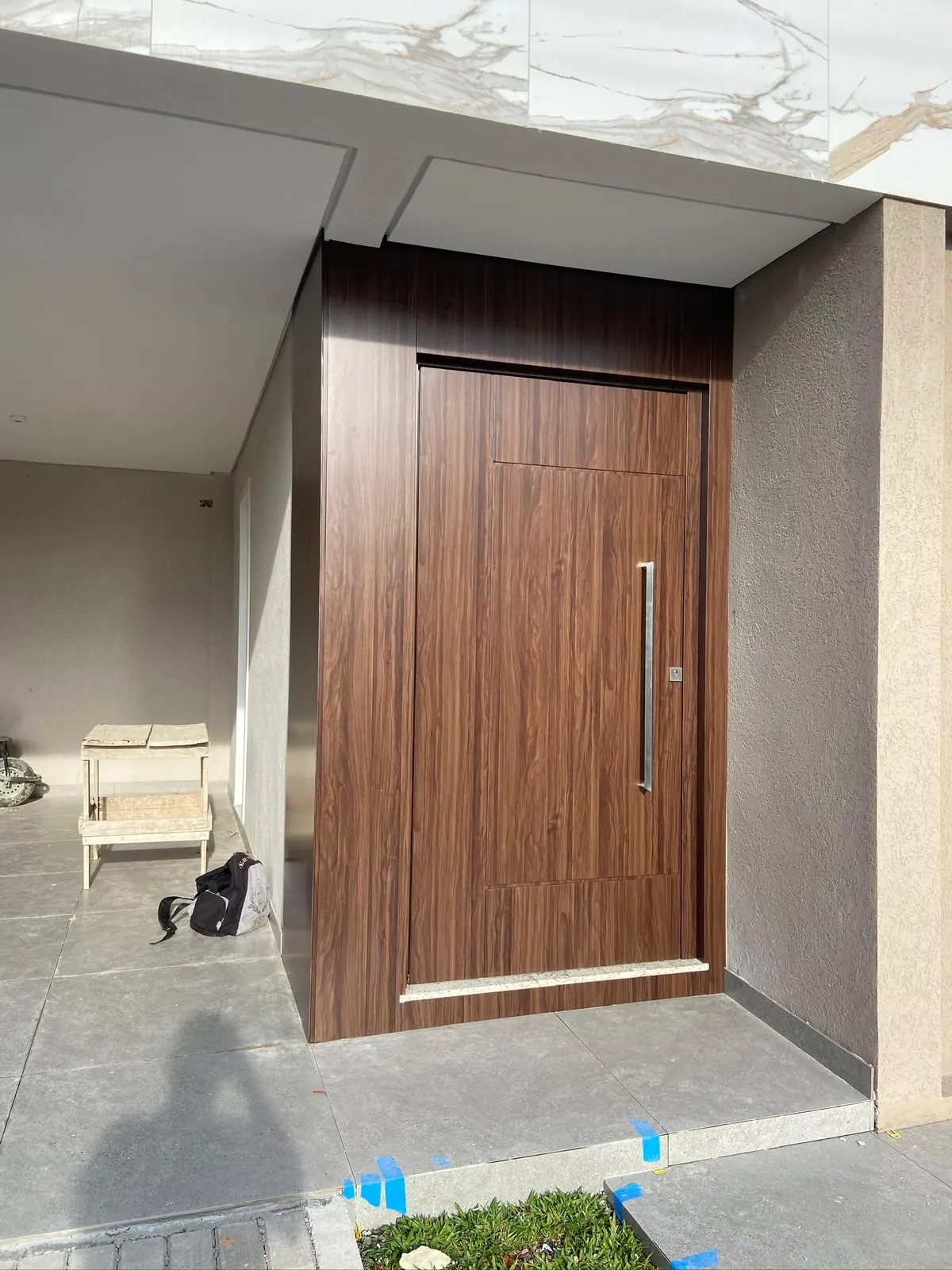 Porta em ACM com acabamento amadeirado nogueira em entrada residencial